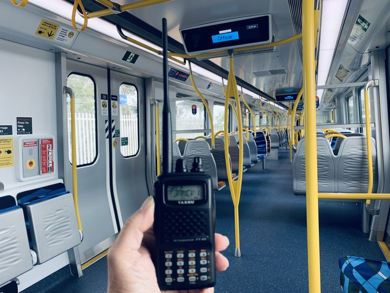 Picture of someone holding a handheld radio on a train
